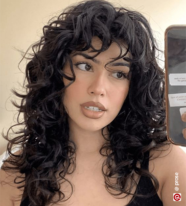 woman in a sleeveless black top and curly shag hair