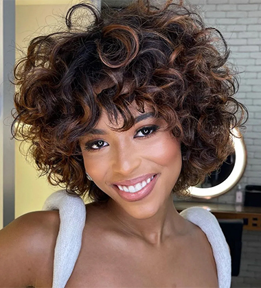 woman in strappy white top and curly short hair