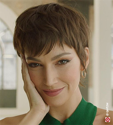 smiling woman wearing a green top resting her face on her hand